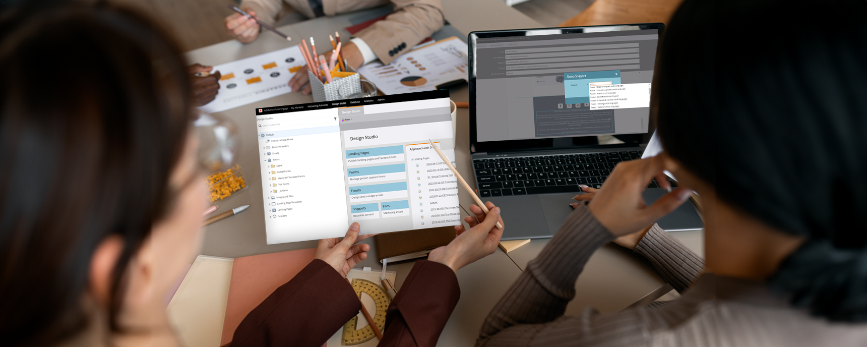 Two screens being looked at by a team. One screen has a screenshot of Marketo snippets, the other shows Marketo's design studio with global assets.