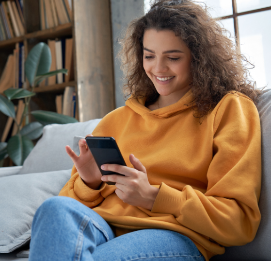 Happy woman smiling while using her smartphone at home, representing JTF Marketing’s expertise in multi-touch attribution to measure true marketing impact.