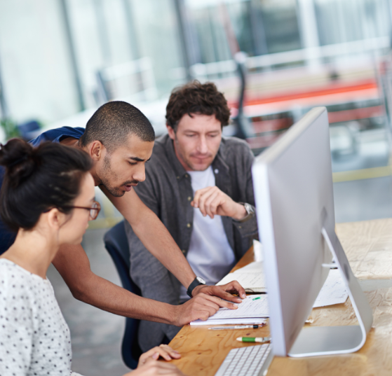 Business professionals collaborating in an office, providing teamwork and problem-solving support, reading, planning, and offering feedback on a computer - symbolizing JTF Marketing’s expertise in platform operations and technical management for Marketo